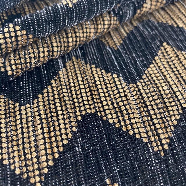 Zigzag pattern printed in gold on a black and silver sheer stretch micro pleated fabric